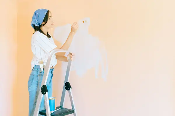 Interior painting in Topeka: painter on a stepladder rolling a wall